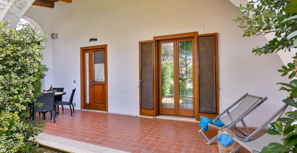Terrazza accogliente con sedie a sdraio, tavolo da pranzo e vista su giardino verde.
