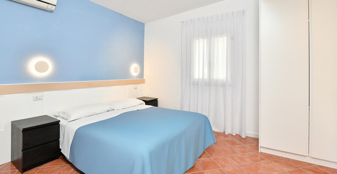 Bungalow accogliente, immerso nel verde, con veranda ombreggiata e finestre blu vivaci.
