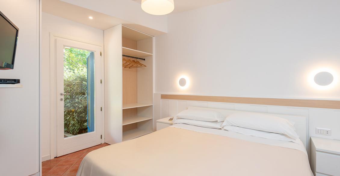 Camera accogliente, luminosa, con letto matrimoniale e tende bianche che filtrano la luce esterna.