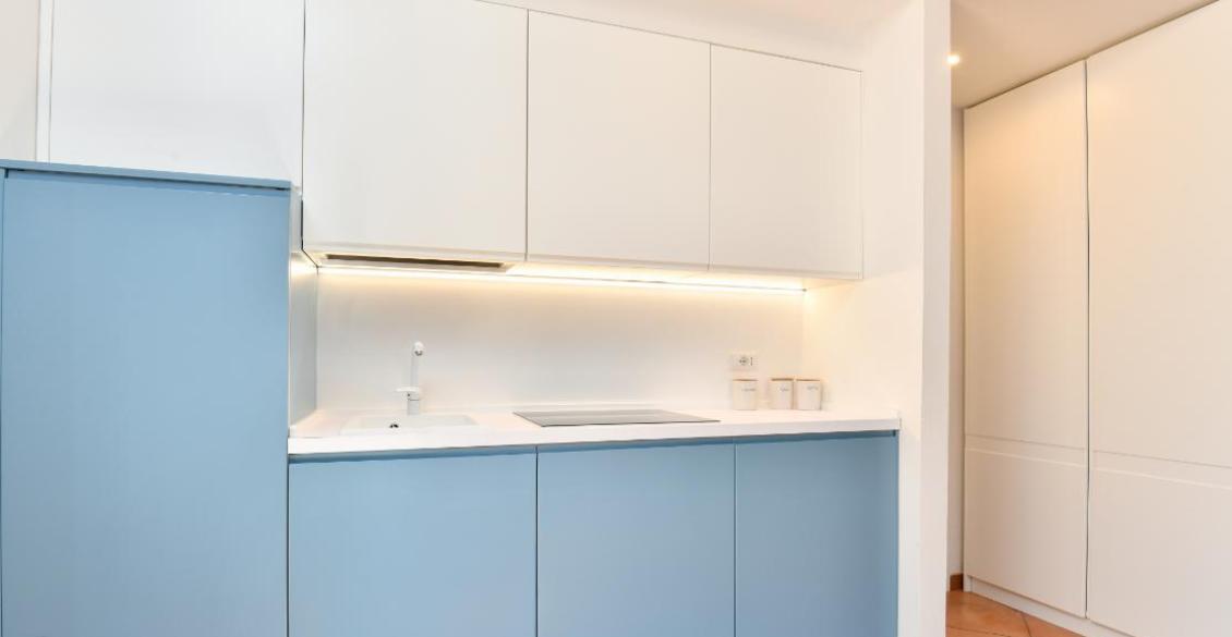 Cucina moderna minimalista, colori bianco e azzurro, atmosfera luminosa e ordinata.