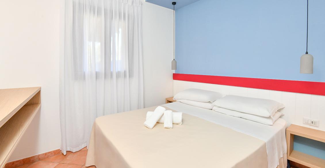 Camera accogliente, luminosa, con letto matrimoniale, pareti azzurre e lampade moderne.