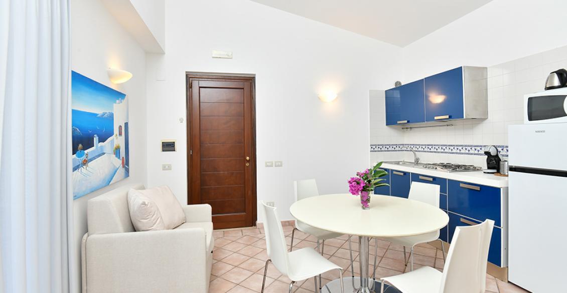 Cucina luminosa, moderna, con mobili blu e tavolo rotondo, atmosfera accogliente.