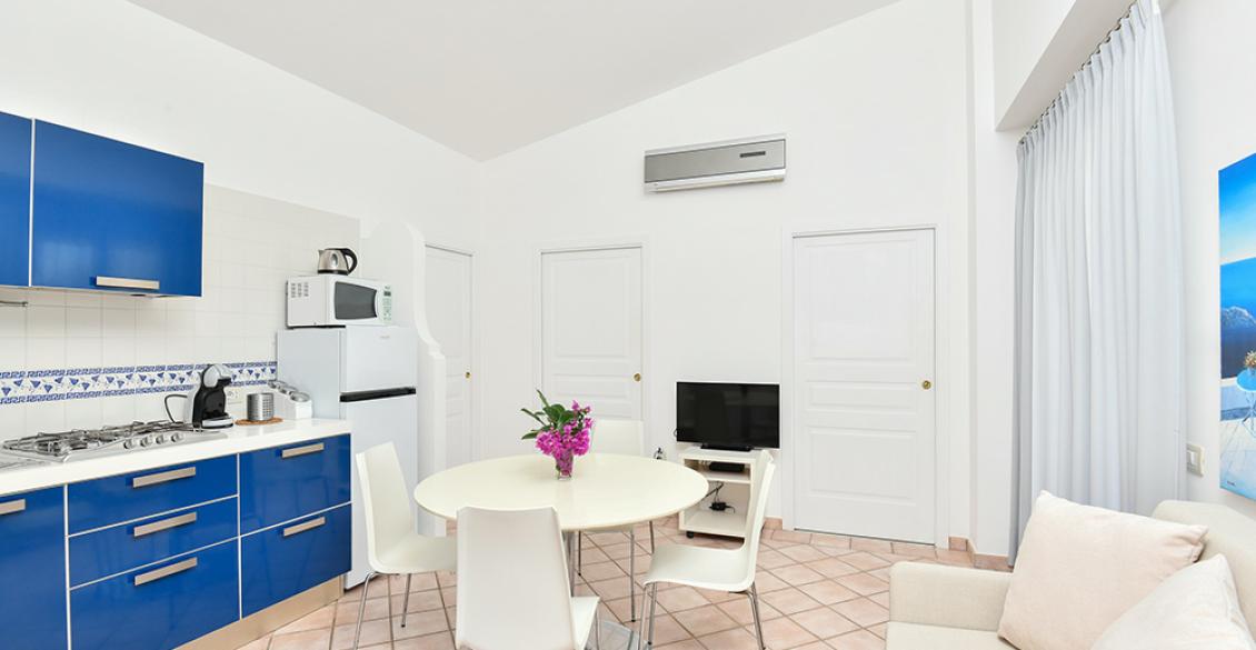 Cucina moderna con mobili blu, tavolo elegante e atmosfera luminosa e accogliente.