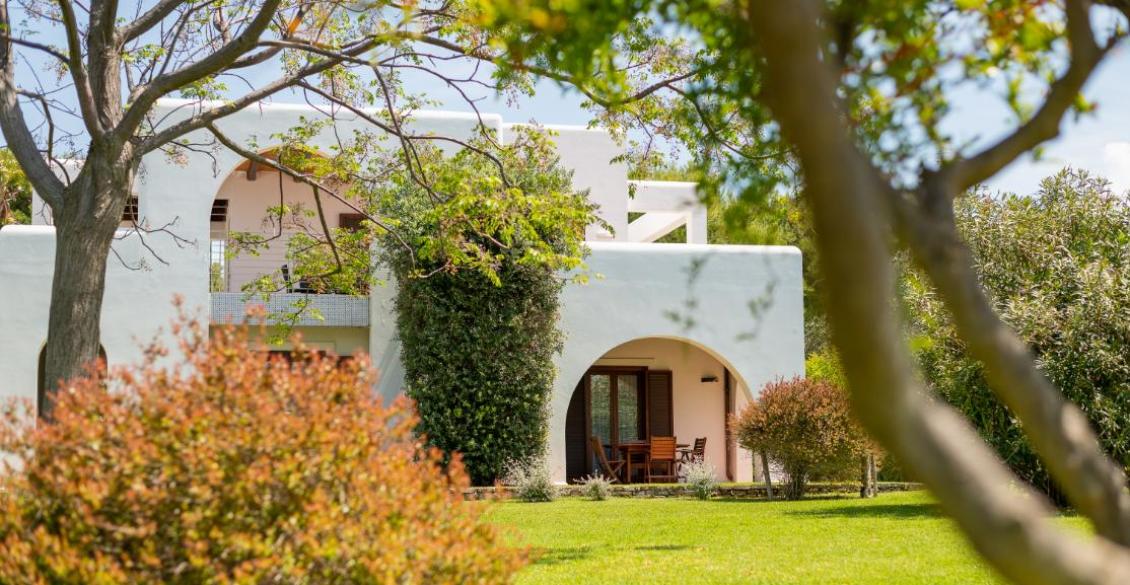 Casa bianca immersa nel verde, con arco e terrazza, atmosfera serena e accogliente.