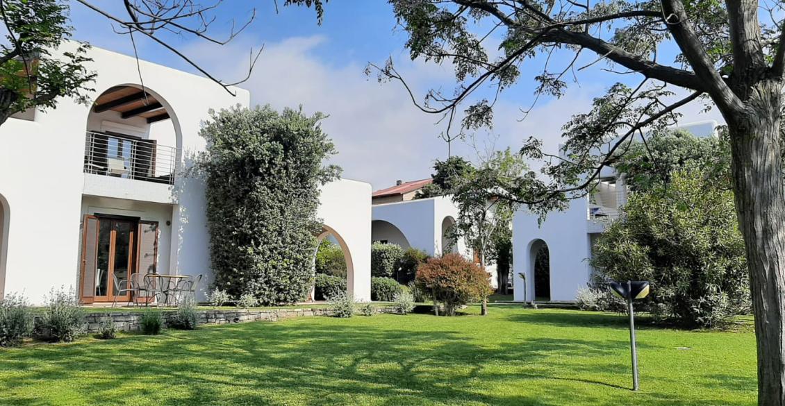 Giardino verde, archi bianchi, natura rigogliosa e cielo azzurro: serenità e armonia.