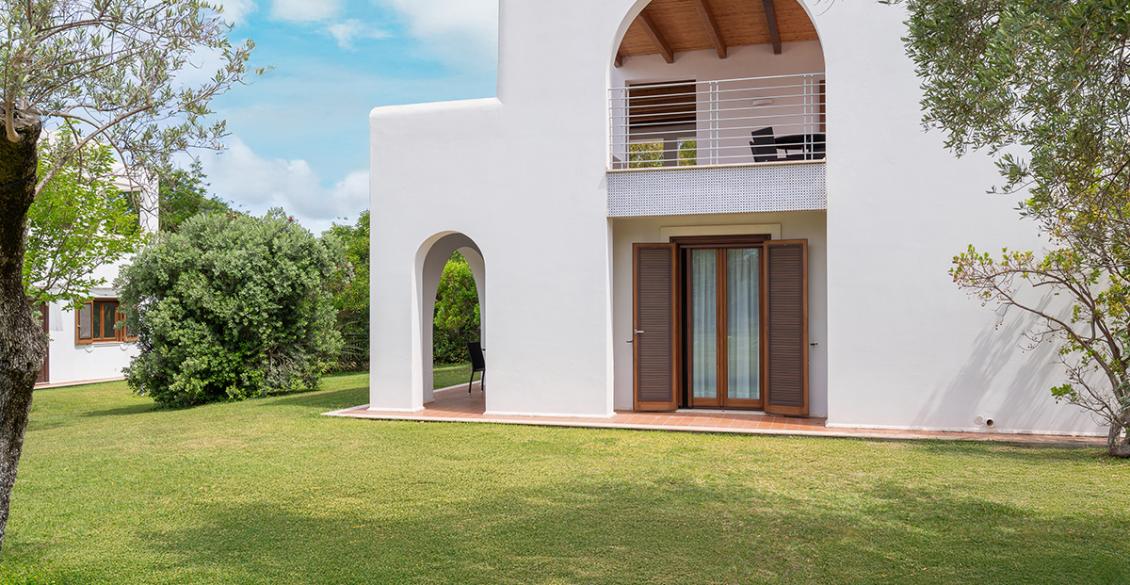 Portico accogliente con tavolo, sedie intrecciate, piante verdi e luce naturale rilassante.