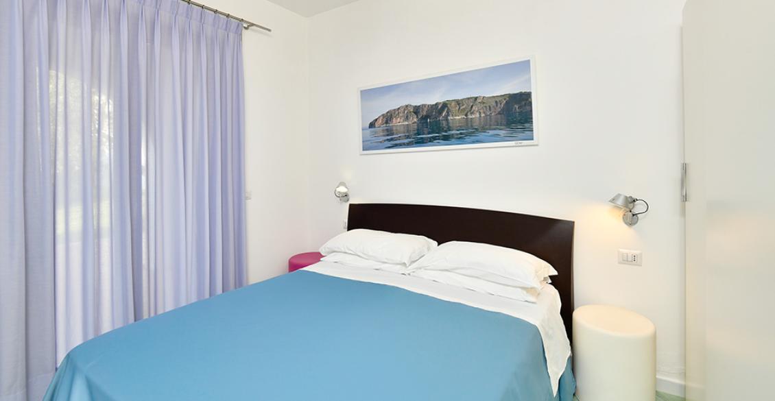 Camera accogliente con letto blu e tenda viola, atmosfera serena.