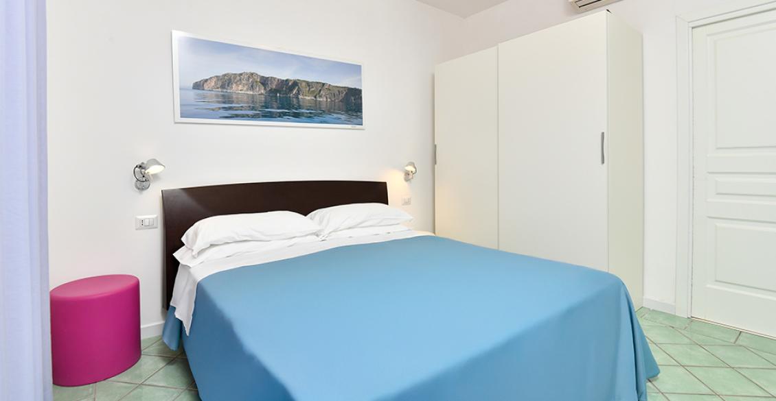 Camera luminosa con letto blu, armadio bianco e aria di tranquillità.