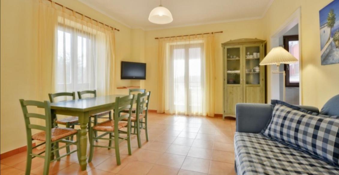 Soggiorno luminoso e accogliente, con tavolo verde, divano a quadri e credenza classica.