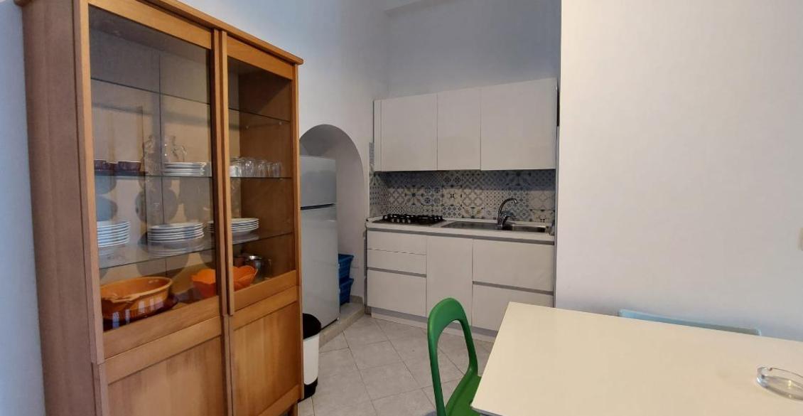 Cucina accogliente con credenza in legno, piastrelle decorate e sedie colorate.
