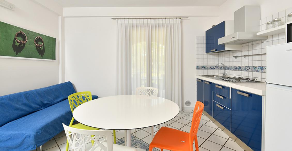 Cucina colorata e luminosa, con sedie vivaci e un divano blu.