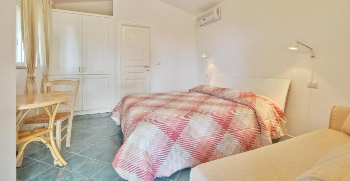 Camera accogliente con letto matrimoniale, copriletto a quadri rossi, atmosfera tranquilla e luminosa.