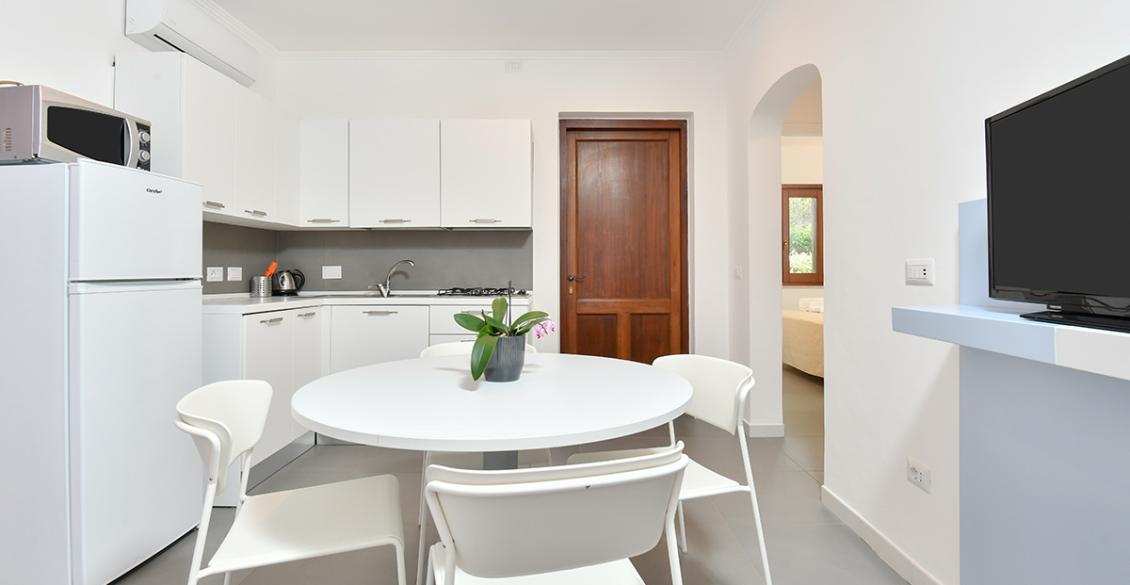 Cucina moderna e luminosa, minimalista con tavolo bianco e pianta decorativa.