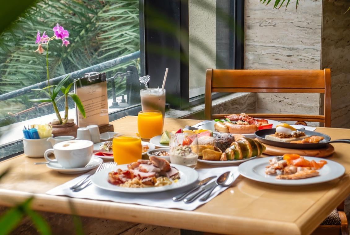 Colazione abbondante e colorata in un ambiente luminoso con fiori e bevande fresche.
