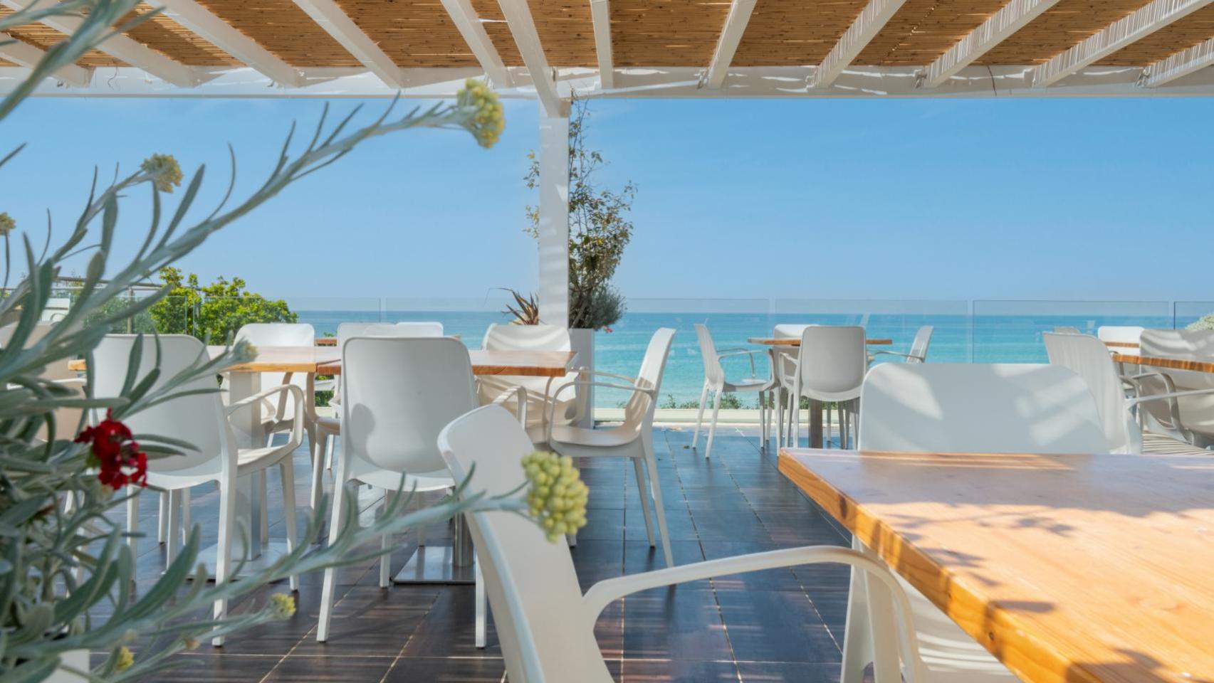 Terrazza sul mare, sedie bianche, atmosfera rilassante e luminosa.