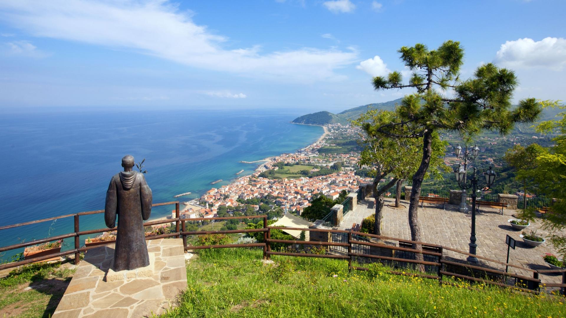 Statua su collina, vista mare e città, atmosfera serena e panoramica.