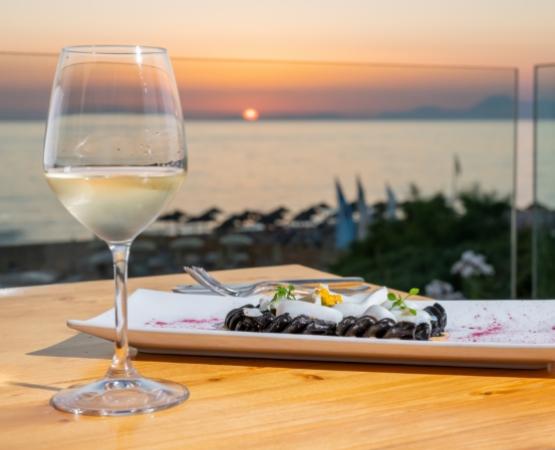 Tramonto sul mare, vino bianco e pasta nera in un'atmosfera di pura serenità.