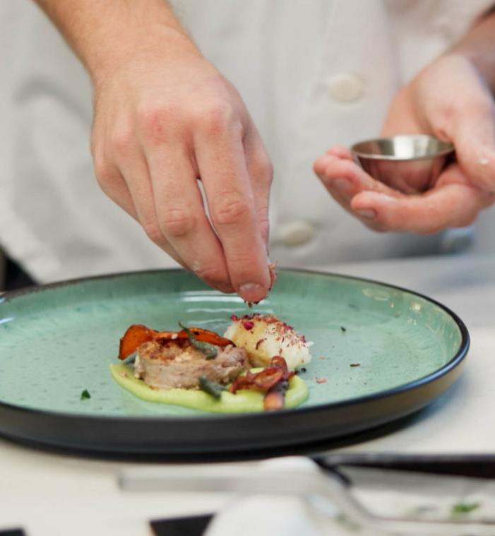Chef rifinisce piatto elegante, colori vivaci, cura nei dettagli, atmosfera di raffinata creatività.