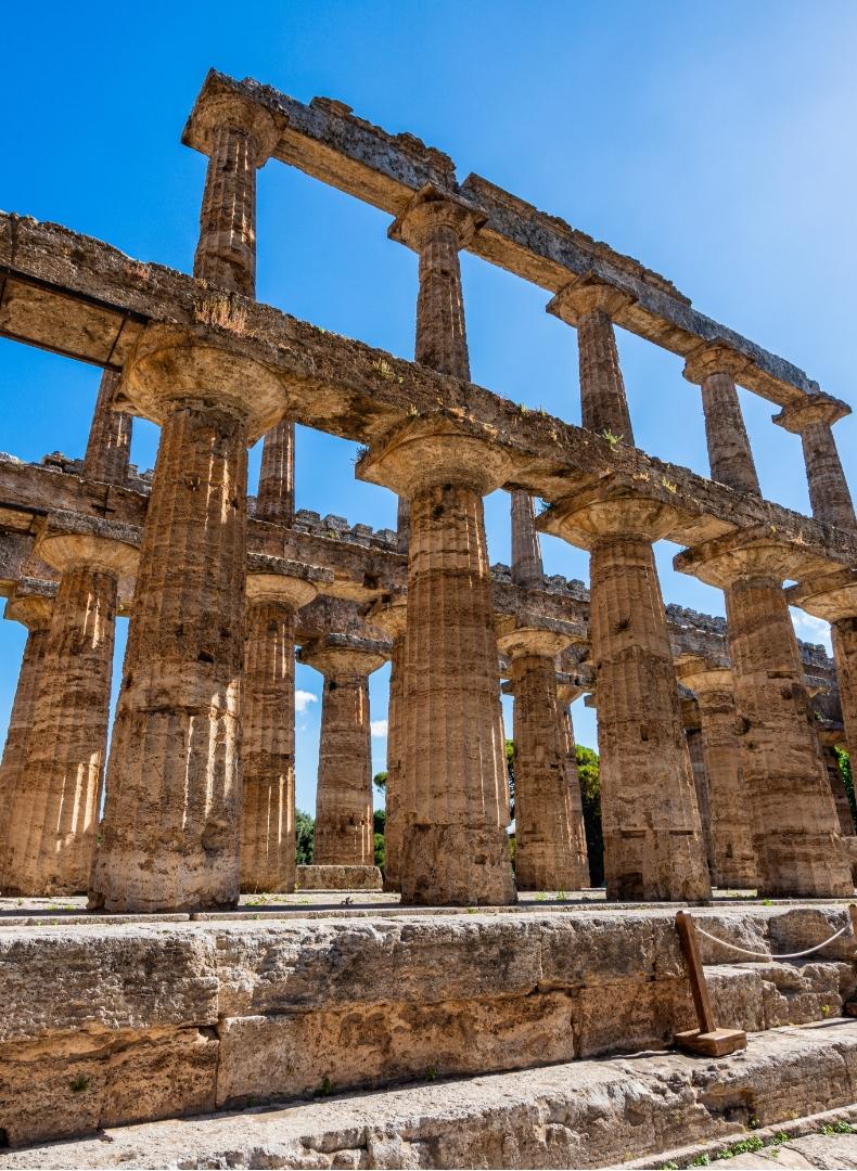 Colonne antiche, maestose, si stagliano contro un cielo azzurro, evocando grandezza e storia.