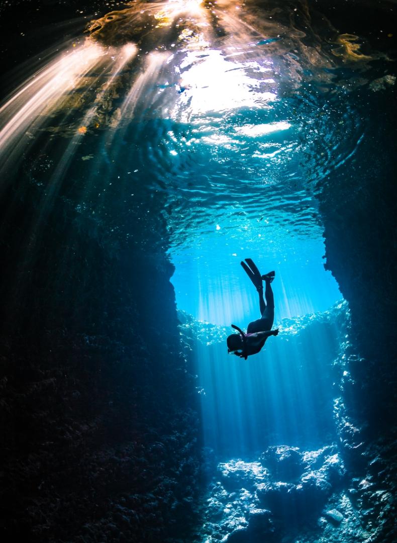 Subacqueo solitario tra raggi di luce in un abisso marino incantevole.