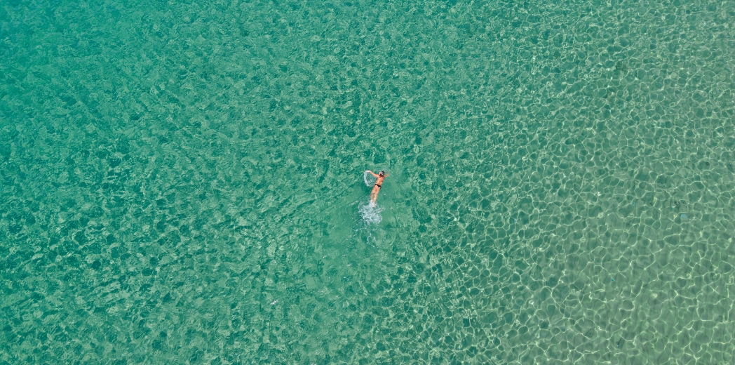 Persona nuota in mare cristallino, trasmette libertà e serenità infinita.